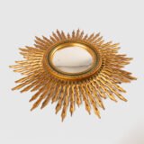 Portuguese Sunburst mirror in gilded carved wood, 1930's. We are pleased to present a splendid Portuguese vintage gilded carved wood sunburst mirror, a unique piece that exudes elegance and sophistication.