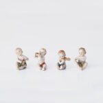 Delicate set of four hand-painted porcelain putti musicians crafted by the Höchst manufactory in Germany, circa 1767–1779. Each figure depicts a different musical instrument and bears the distinctive Höchst wheel mark with radiating spokes. Approx. 1.77 × 1.77 × 1.18 in. A fine example of late Rococo artistry.