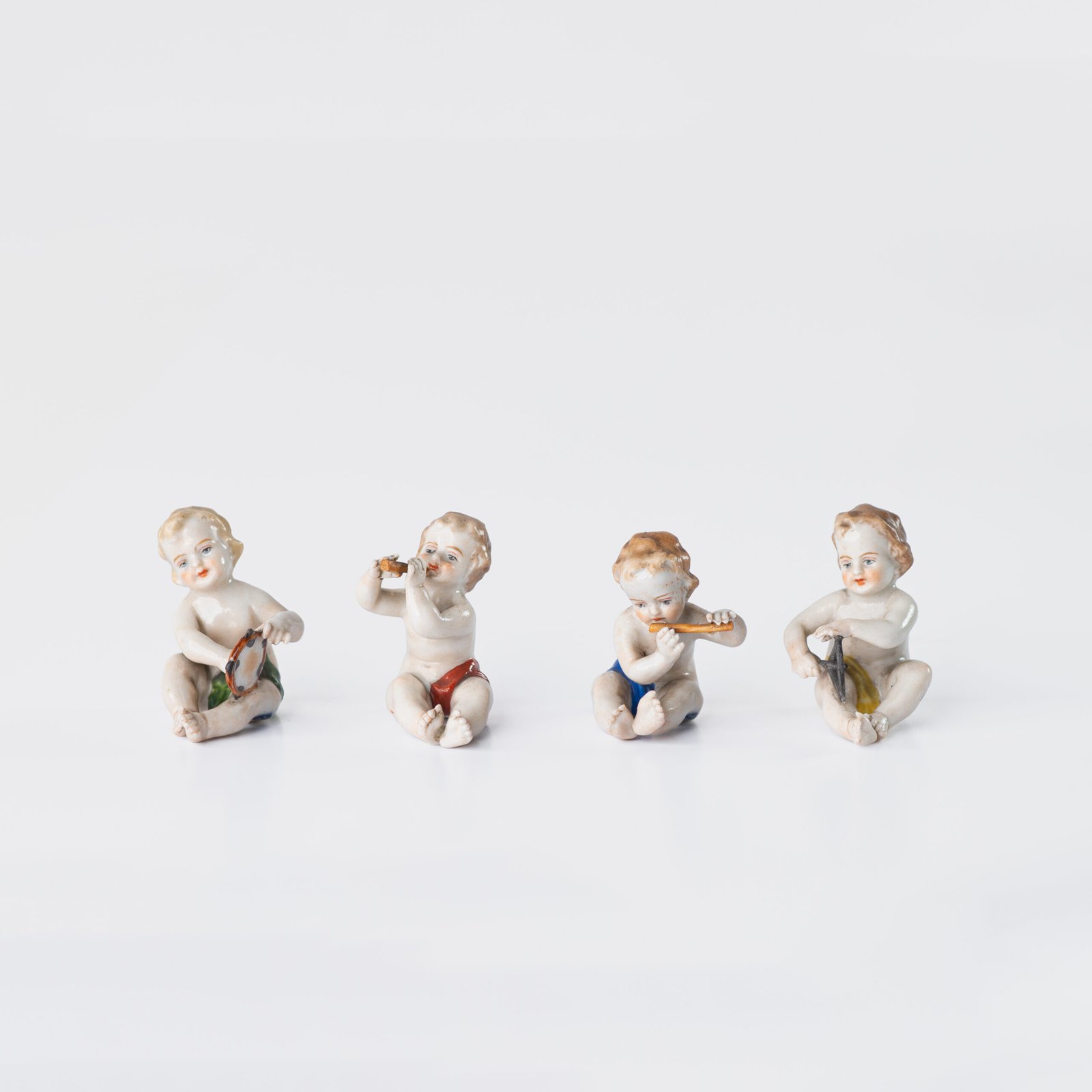 Delicate set of four hand-painted porcelain putti musicians crafted by the Höchst manufactory in Germany, circa 1767–1779. Each figure depicts a different musical instrument and bears the distinctive Höchst wheel mark with radiating spokes. Approx. 1.77 × 1.77 × 1.18 in. A fine example of late Rococo artistry.