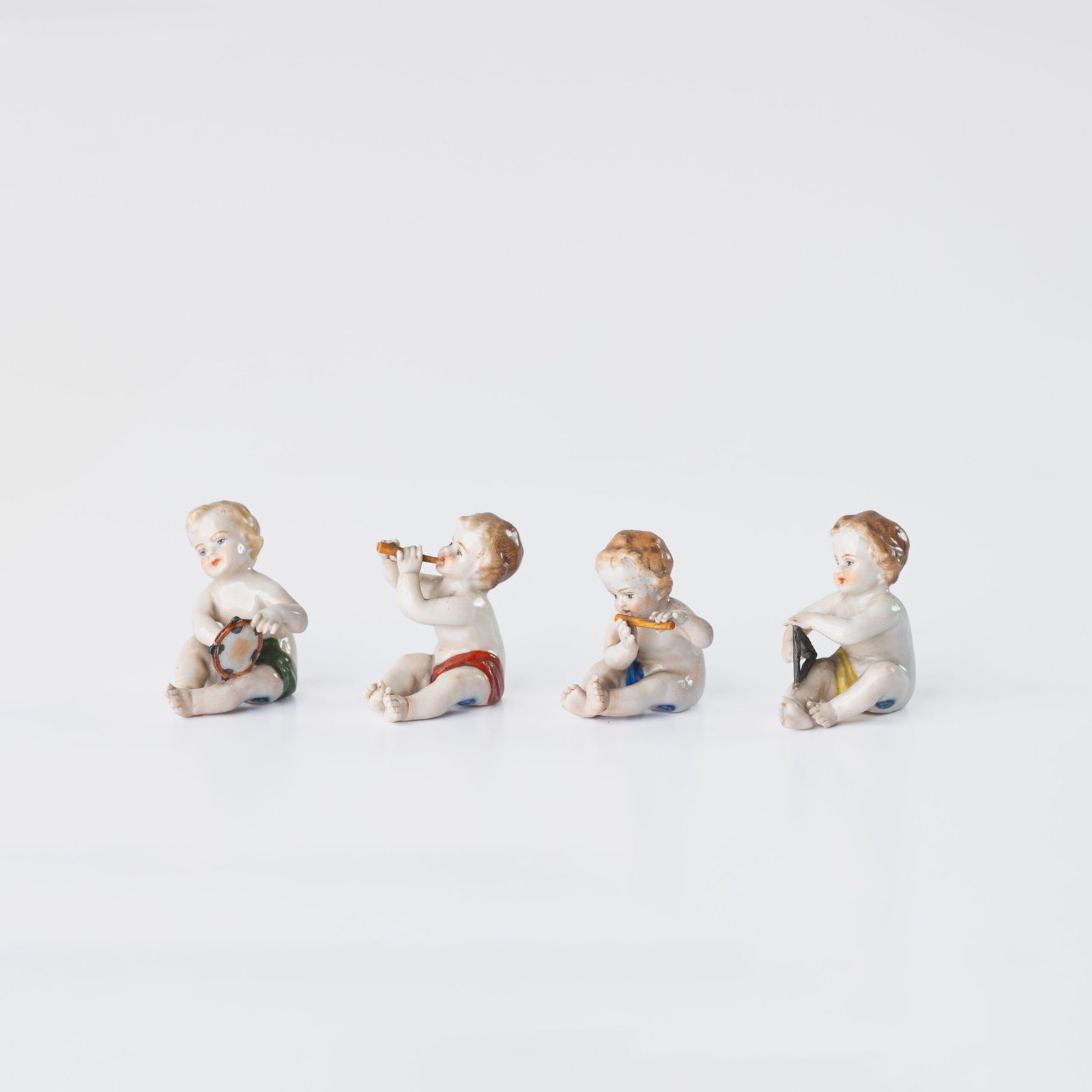 Delicate set of four hand-painted porcelain putti musicians crafted by the Höchst manufactory in Germany, circa 1767–1779. Each figure depicts a different musical instrument and bears the distinctive Höchst wheel mark with radiating spokes. Approx. 1.77 × 1.77 × 1.18 in. A fine example of late Rococo artistry.