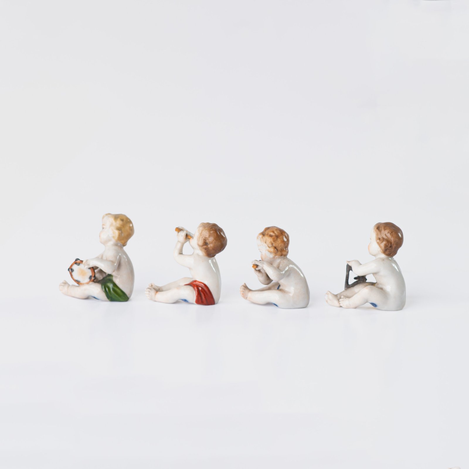 Delicate set of four hand-painted porcelain putti musicians crafted by the Höchst manufactory in Germany, circa 1767–1779. Each figure depicts a different musical instrument and bears the distinctive Höchst wheel mark with radiating spokes. Approx. 1.77 × 1.77 × 1.18 in. A fine example of late Rococo artistry.