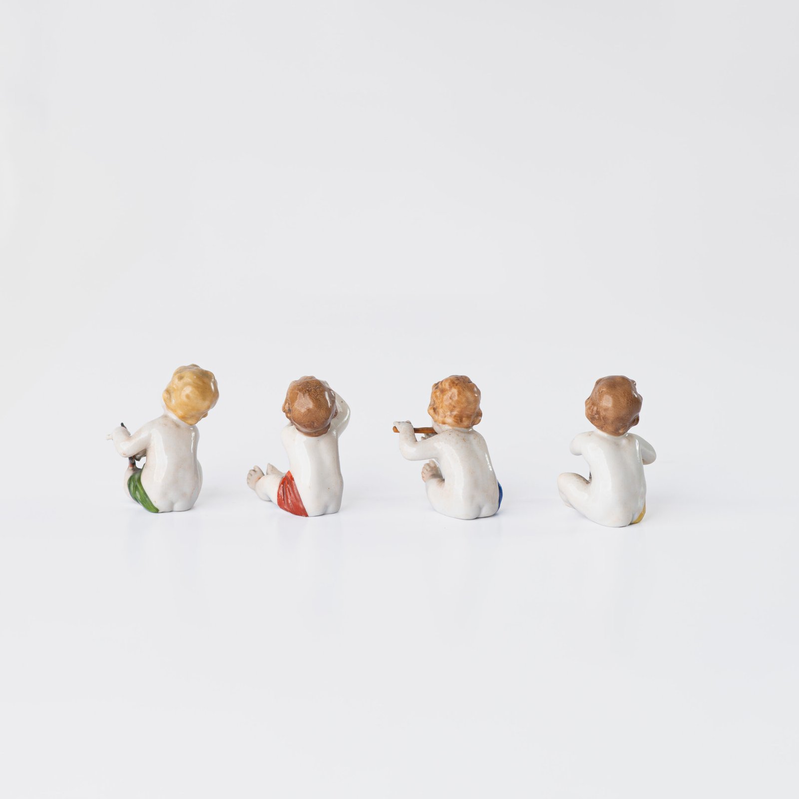 Delicate set of four hand-painted porcelain putti musicians crafted by the Höchst manufactory in Germany, circa 1767–1779. Each figure depicts a different musical instrument and bears the distinctive Höchst wheel mark with radiating spokes. Approx. 1.77 × 1.77 × 1.18 in. A fine example of late Rococo artistry.