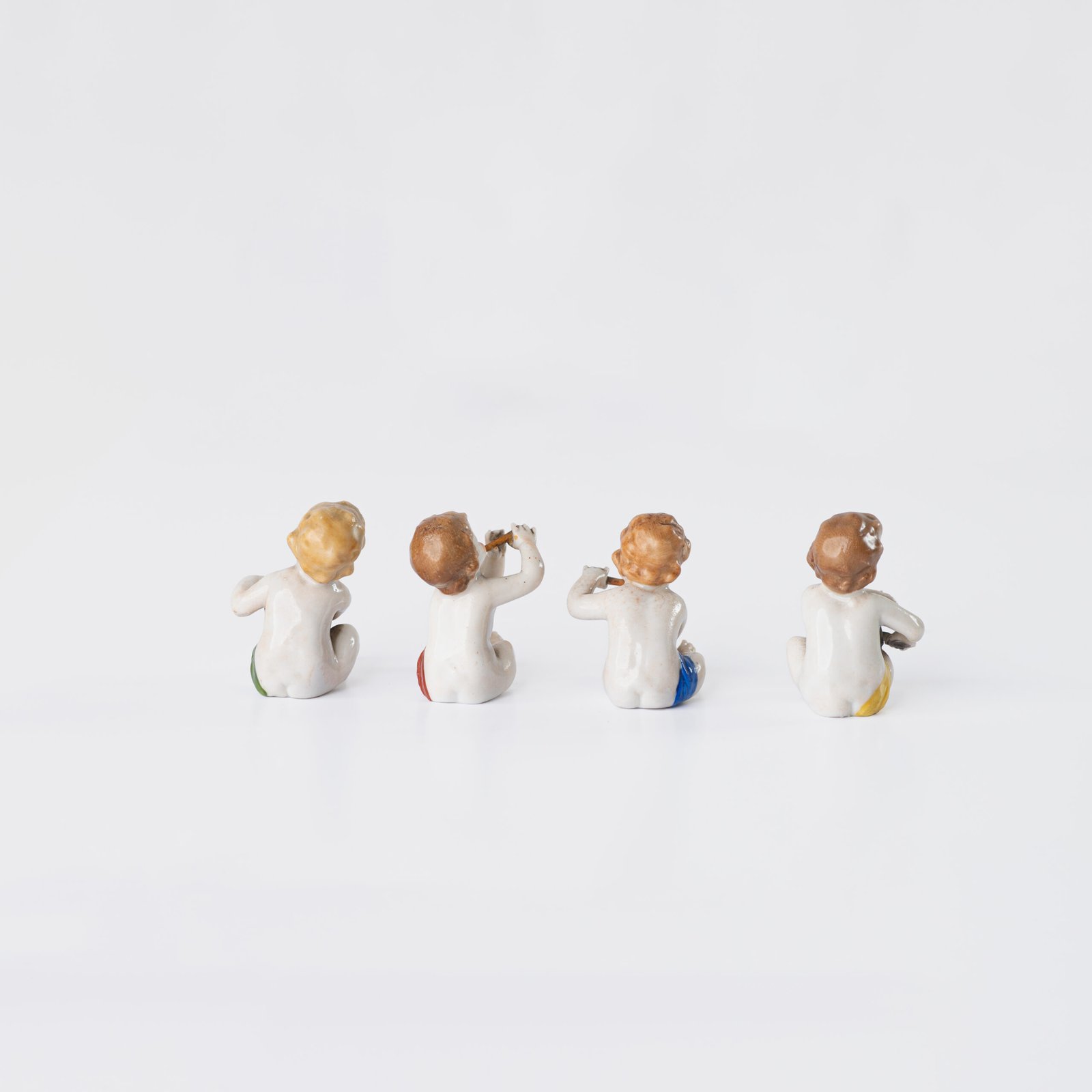 Delicate set of four hand-painted porcelain putti musicians crafted by the Höchst manufactory in Germany, circa 1767–1779. Each figure depicts a different musical instrument and bears the distinctive Höchst wheel mark with radiating spokes. Approx. 1.77 × 1.77 × 1.18 in. A fine example of late Rococo artistry.