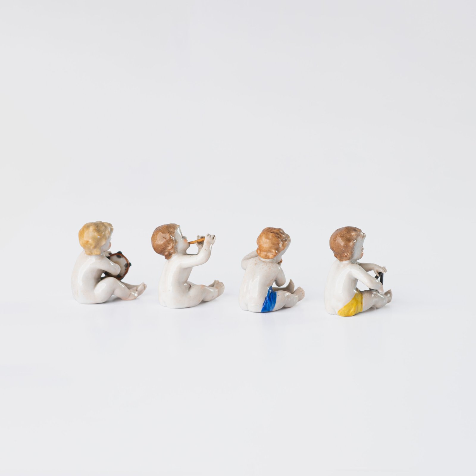 Delicate set of four hand-painted porcelain putti musicians crafted by the Höchst manufactory in Germany, circa 1767–1779. Each figure depicts a different musical instrument and bears the distinctive Höchst wheel mark with radiating spokes. Approx. 1.77 × 1.77 × 1.18 in. A fine example of late Rococo artistry.