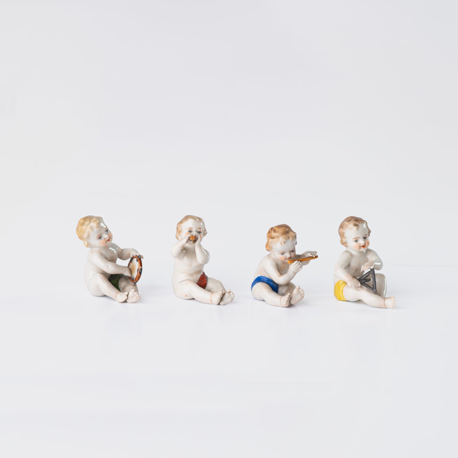 Delicate set of four hand-painted porcelain putti musicians crafted by the Höchst manufactory in Germany, circa 1767–1779. Each figure depicts a different musical instrument and bears the distinctive Höchst wheel mark with radiating spokes. Approx. 1.77 × 1.77 × 1.18 in. A fine example of late Rococo artistry.