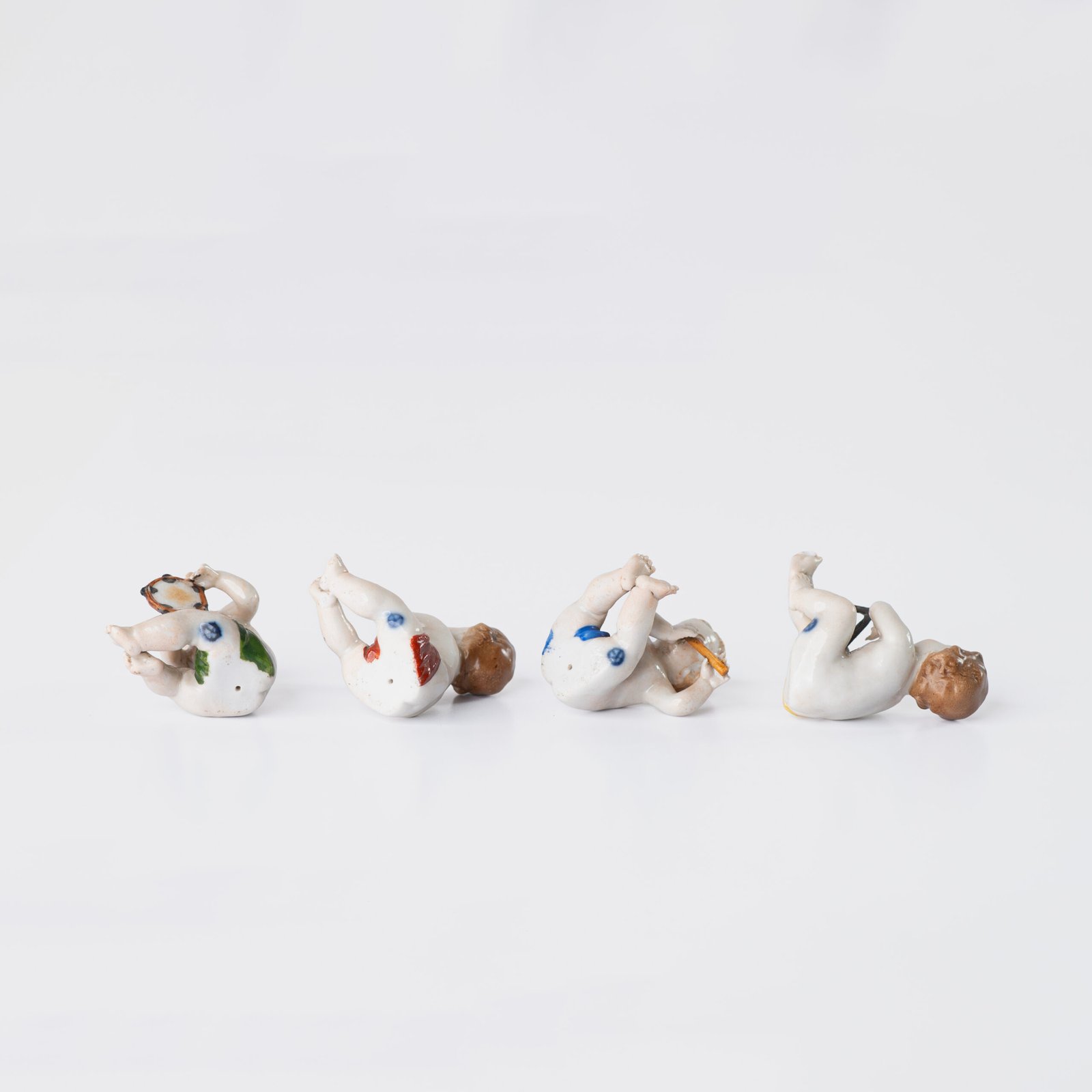 Delicate set of four hand-painted porcelain putti musicians crafted by the Höchst manufactory in Germany, circa 1767–1779. Each figure depicts a different musical instrument and bears the distinctive Höchst wheel mark with radiating spokes. Approx. 1.77 × 1.77 × 1.18 in. A fine example of late Rococo artistry.