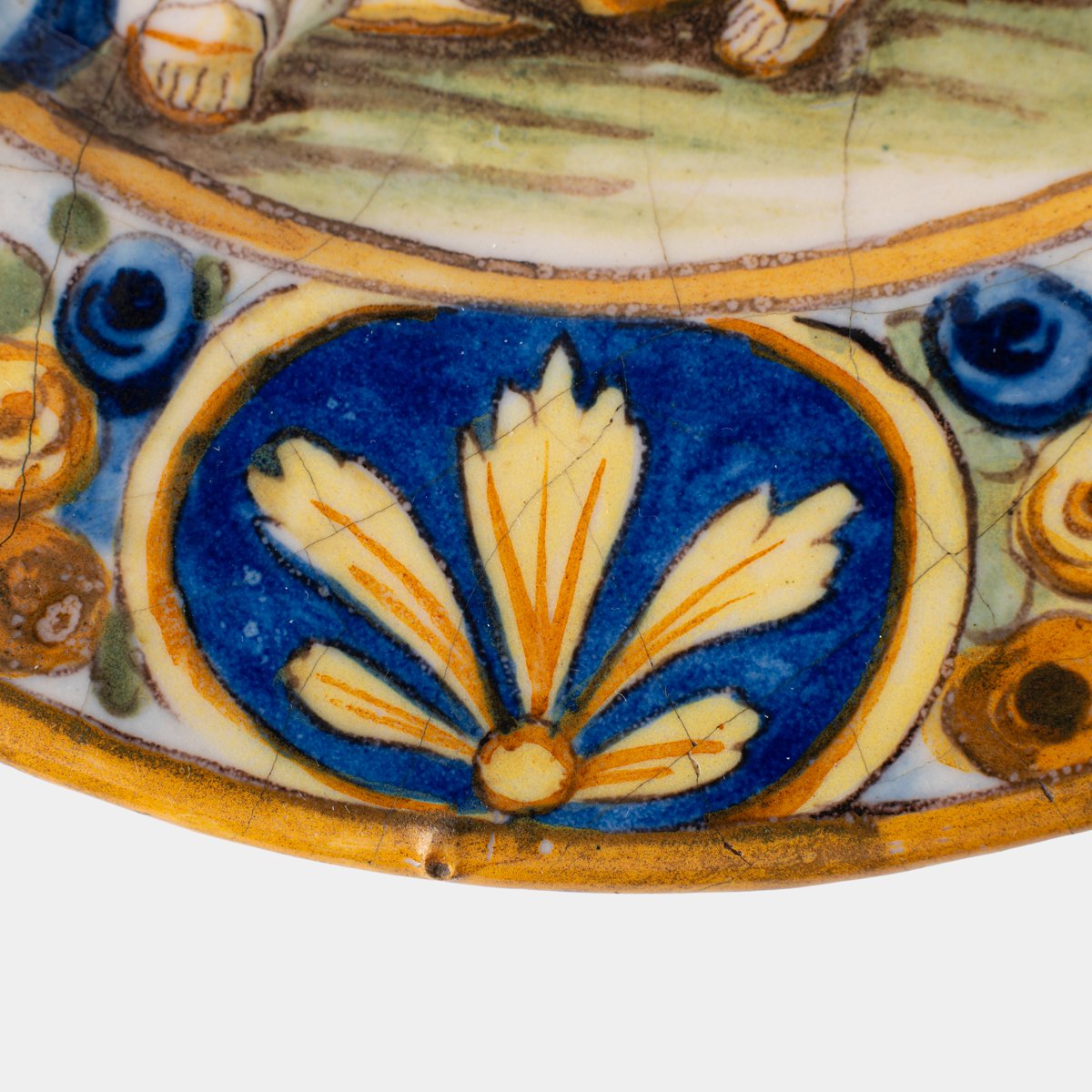 Hand-painted Italian maiolica plate, Deruta or Urbino, late 17th to early 18th century. Depicts Mercury with winged sandals beside a female figure, likely an allegory of Peace, Concord, or Wisdom. Rich Baroque border with cherubs, musical instruments, and cartouches. Tin-glazed earthenware with visible craquelure and minor rim losses.