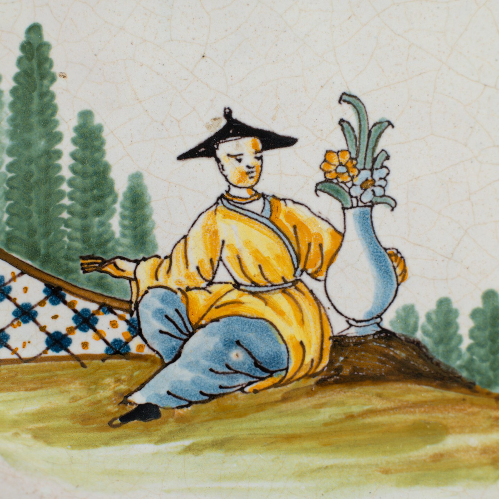 Oval faience plate, France, ca. 1760–1790, attributed to Rouen; tin-glazed earthenware with hand-painted chinoiserie scene in enamel pigments (cobalt, manganese, copper, antimony); figures in stylized garden within manganese-lined scalloped rim; ivory glaze with fine, stable craquelure
