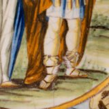 Hand-painted Italian maiolica plate, Deruta or Urbino, late 17th to early 18th century. Depicts Mercury with winged sandals beside a female figure, likely an allegory of Peace, Concord, or Wisdom. Rich Baroque border with cherubs, musical instruments, and cartouches. Tin-glazed earthenware with visible craquelure and minor rim losses.