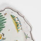 Oval faience plate, France, ca. 1760–1790, attributed to Rouen; tin-glazed earthenware with hand-painted chinoiserie scene in enamel pigments (cobalt, manganese, copper, antimony); figures in stylized garden within manganese-lined scalloped rim; ivory glaze with fine, stable craquelure