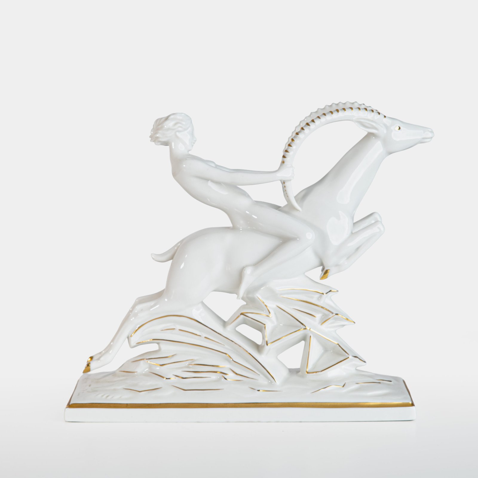 Glazed white porcelain sculpture signed by Max Hermann Fritz and produced by Hutschenreuther Selb between 1925 and 1935. Depicts a nude female figure riding a leaping ibex, with hand-applied gilding on the horns, eyes, hooves, and base. German Art Deco style.