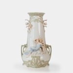 Art Nouveau porcelain vase by Karl Ens, circa 1900, featuring a sculptural composition in high relief with a maiden and cherub, hand-painted with floral details and highlighted with gilding. Marked “KVE” on the base.