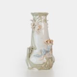 Art Nouveau porcelain vase by Karl Ens, circa 1900, featuring a sculptural composition in high relief with a maiden and cherub, hand-painted with floral details and highlighted with gilding. Marked “KVE” on the base.
