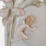 Art Nouveau porcelain vase by Karl Ens, circa 1900, featuring a sculptural composition in high relief with a maiden and cherub, hand-painted with floral details and highlighted with gilding. Marked “KVE” on the base.