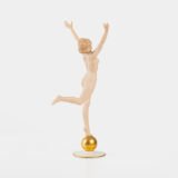Karl Tutter porcelain figurine “Sonnenkind” – Art Deco sculpture by Hutschenreuther Germany, c.1935–1940 Art Deco porcelain figurine titled “Sonnenkind” (“Sun Child”), modeled by Karl Tutter for Hutschenreuther ca. 1935–1940. Depicts a nude young woman balancing on a golden sphere, arms extended in a dynamic pose. White porcelain with a matte pinkish flesh-tone finish, painted facial features, and satin brown hair. Gilded accents on the sphere and base. Rare signed version with circular base and gold trim.