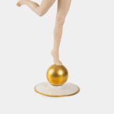 Karl Tutter porcelain figurine “Sonnenkind” – Art Deco sculpture by Hutschenreuther Germany, c.1935–1940 Art Deco porcelain figurine titled “Sonnenkind” (“Sun Child”), modeled by Karl Tutter for Hutschenreuther ca. 1935–1940. Depicts a nude young woman balancing on a golden sphere, arms extended in a dynamic pose. White porcelain with a matte pinkish flesh-tone finish, painted facial features, and satin brown hair. Gilded accents on the sphere and base. Rare signed version with circular base and gold trim.