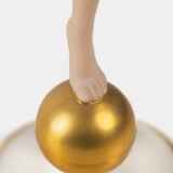 Karl Tutter porcelain figurine “Sonnenkind” – Art Deco sculpture by Hutschenreuther Germany, c.1935–1940 Art Deco porcelain figurine titled “Sonnenkind” (“Sun Child”), modeled by Karl Tutter for Hutschenreuther ca. 1935–1940. Depicts a nude young woman balancing on a golden sphere, arms extended in a dynamic pose. White porcelain with a matte pinkish flesh-tone finish, painted facial features, and satin brown hair. Gilded accents on the sphere and base. Rare signed version with circular base and gold trim.