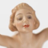 Karl Tutter porcelain figurine “Sonnenkind” – Art Deco sculpture by Hutschenreuther Germany, c.1935–1940 Art Deco porcelain figurine titled “Sonnenkind” (“Sun Child”), modeled by Karl Tutter for Hutschenreuther ca. 1935–1940. Depicts a nude young woman balancing on a golden sphere, arms extended in a dynamic pose. White porcelain with a matte pinkish flesh-tone finish, painted facial features, and satin brown hair. Gilded accents on the sphere and base. Rare signed version with circular base and gold trim.