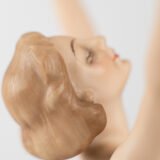 Karl Tutter porcelain figurine “Sonnenkind” – Art Deco sculpture by Hutschenreuther Germany, c.1935–1940 Art Deco porcelain figurine titled “Sonnenkind” (“Sun Child”), modeled by Karl Tutter for Hutschenreuther ca. 1935–1940. Depicts a nude young woman balancing on a golden sphere, arms extended in a dynamic pose. White porcelain with a matte pinkish flesh-tone finish, painted facial features, and satin brown hair. Gilded accents on the sphere and base. Rare signed version with circular base and gold trim.