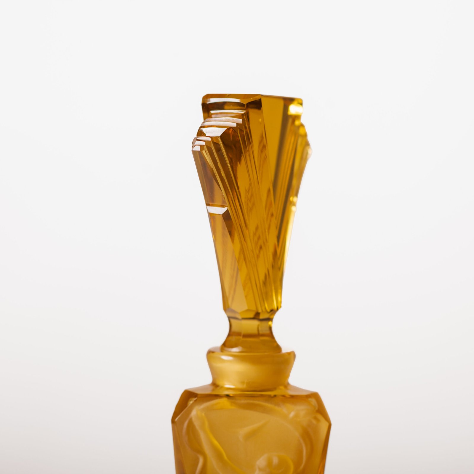 Large German Art Deco perfume bottle in satin-finished pressed amber glass, c. 1930, with figurative relief panels of nude female figures in different poses, faceted geometric base and tall fan-shaped stopper; height 29 cm / 11.42 in, width 9.5 cm / 3.74 in.