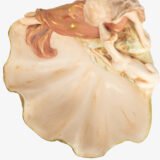 Royal Dux Art Nouveau porcelain centerpiece with a seated maiden and fawn beside a green shell-shaped bowl, hand-painted with gilt highlights, circa 1920–1930.