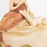 Royal Dux Art Nouveau porcelain centerpiece with a seated maiden and fawn beside a green shell-shaped bowl, hand-painted with gilt highlights, circa 1920–1930.