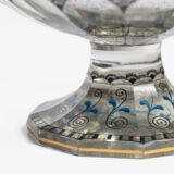 Bohemian Glass Compote, c. 1915, with hand-enamelled birds in scalloped blue panels, geometric glass cutting, gilt rim and a faceted foot decorated with black scrolls and blue leaves.