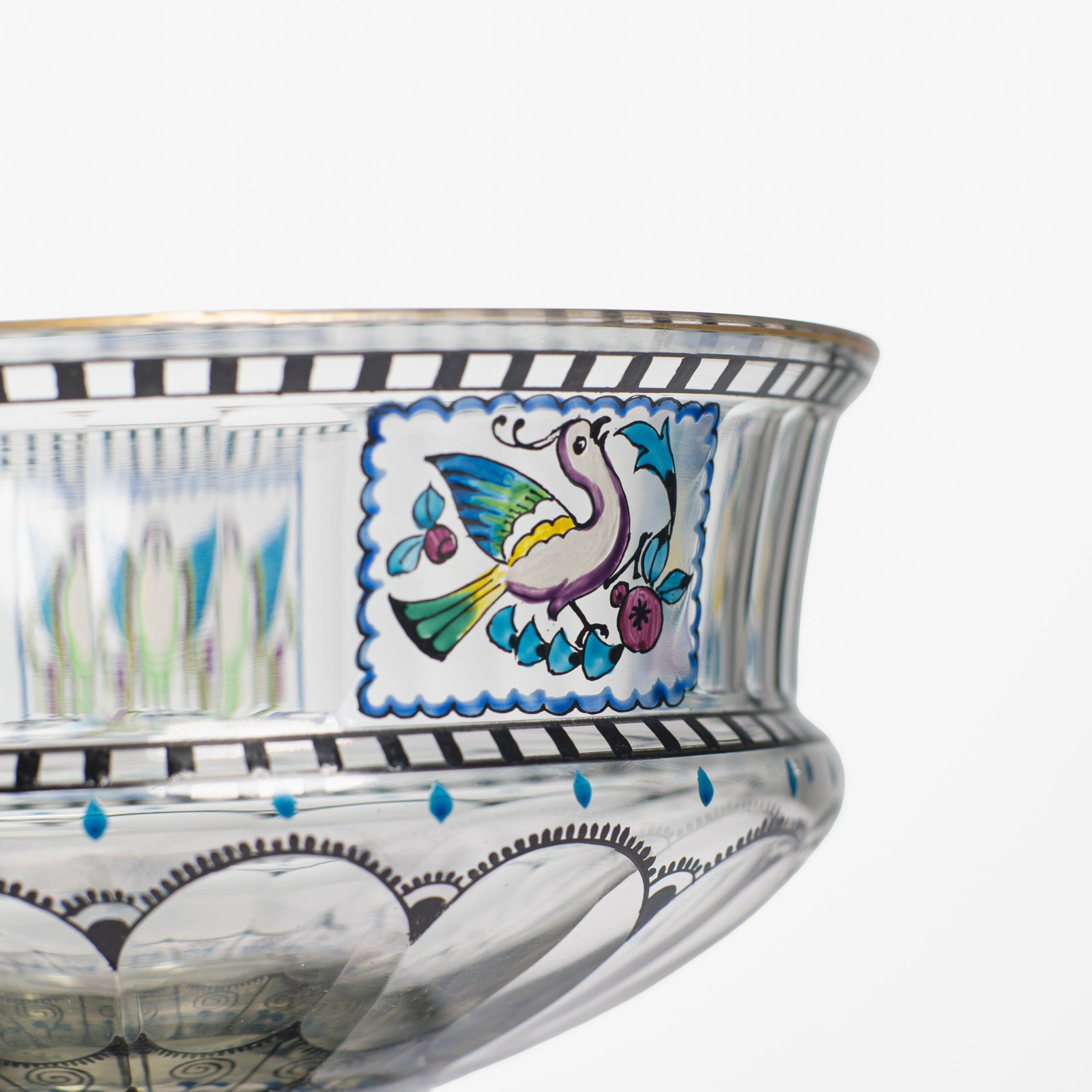 Bohemian Glass Compote, c. 1915, with hand-enamelled birds in scalloped blue panels, geometric glass cutting, gilt rim and a faceted foot decorated with black scrolls and blue leaves.